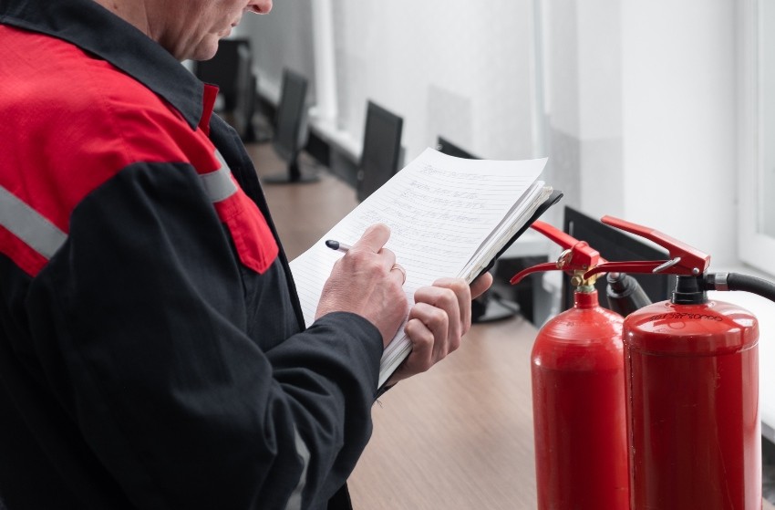Techniker prueft Feuerloescher - Brandschutz und Versicherungsschutz