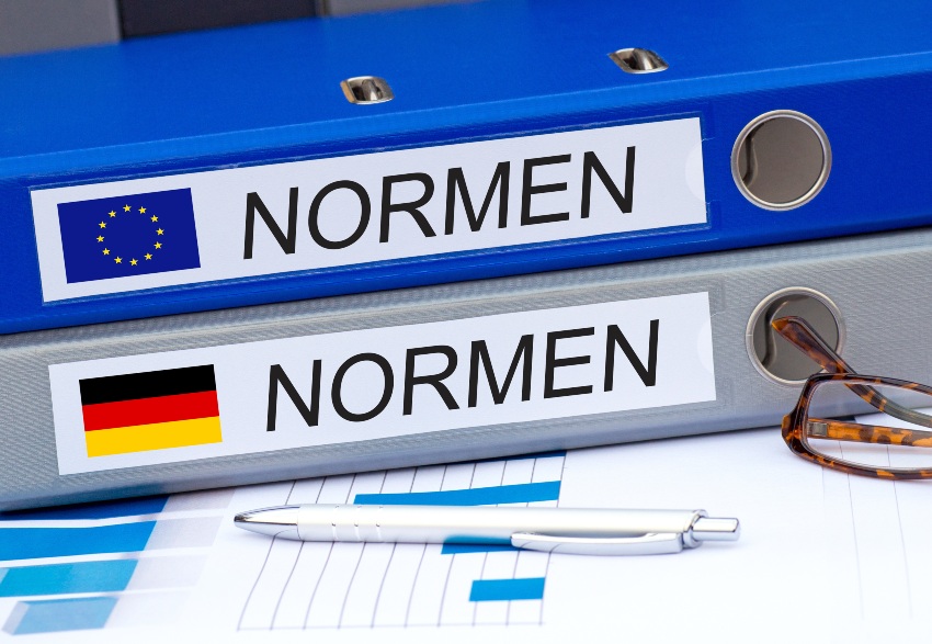 In Deutschland regelt die DIN Norm 14675 die 4 Kategorien der Brandmeldeanlage Symbolbild, 2 Aktenordner mit "Normen" beschriftet - Welche Brandmeldeanlagen-Kategorien und Schutzarten gibt es?